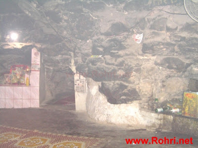 Mystical Cave Interior with Offerings Low-ceilinged cave of Kalka Devi adorned with flowers, incense, and devotional offerings on stone shelves