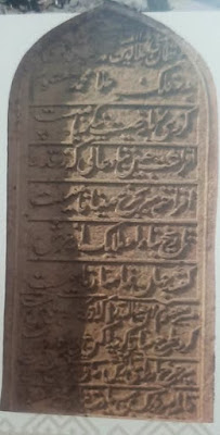 The Persian Inscription: A Poetic Tribute A historic minaret and domed structure with intricate brickwork and turquoise tile decorations, showcasing Mughal architecture under a clear blue sky.