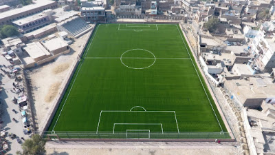 Sunrise Drone View of Gangoti Ground, Rohri 2025 Aerial drone image capturing the sunrise over Gangoti Ground in Rohri, Sindh, with golden light illuminating the historic football field and surrounding area in 2025.