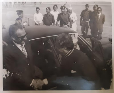 Ghulam Siddique Qadri in police uniform stands beside a car during the ceremonial airport reception in Karachi for Mohammad Reza Pahlavi, Shah of Iran Ghulam Siddique Qadri in police uniform stands beside a car during the ceremonial airport reception in Karachi for Mohammad Reza Pahlavi, Shah of Iran. Other uniformed officers and dignitaries are present."