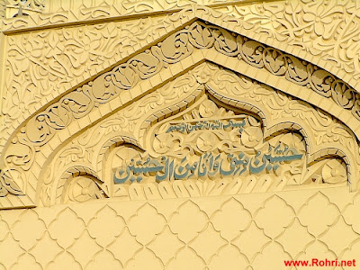 “Hussain Is From Me, and I Am From Hussain” – Sacred Inscription at Jan Allah Shah Shrine, Rohri Arabic calligraphy of "Hussainu minni wa ana minal Hussain" inscribed on the shrine of Jan Allah Shah Janshahi in Rohri, Sindh. Surrounded by ornate Islamic floral carvings.