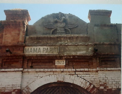 Mama Parsi Heritage Building – Established 1923, Sukkur ed brick facade with arched entrance and a sign reading “MAMA PARSI 1923,” topped by a sculpted Faravahar emblem.