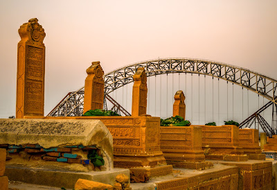 Carved Graves of Sateen Jo Aastan: Makli-Style Stonework with Lansdowne Bridge View in Rohri, Pakistan Makli-style carved stone graves at Sateen Jo Aastan with Lansdowne Bridge in background, right-side view, Rohri, Sindh, Pakistan