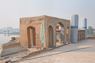 Rooftop Graves of Sateen Jo Aastan: Carved Pinnacles in Rohri, Pakistan Intricately carved stone graves with conical pinnacles at Sateen Jo Aastan rooftop, city skyline in background, Rohri, Sindh, Pakistan
