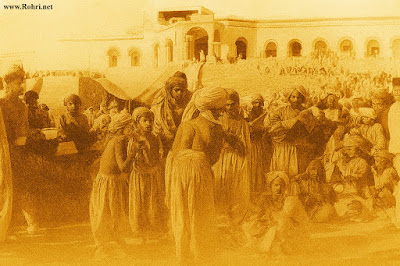 Grand Inauguration of Sukkur DC and Treasury Offices, 1901 Black-and-white historical photograph showing a large crowd assembled on an open maidan below the newly constructed red-brick Deputy Commissioner Office in Sukkur, with British officials in formal attire cutting a ribbon amid local dignitaries and onlookers, 1901.