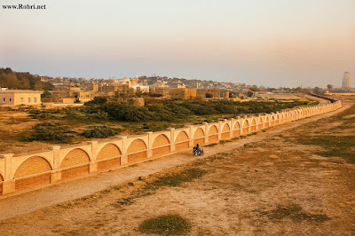 Northern Rohri Riverside β Historic British Military Outpost View of northern Rohri near the Indus River, once a strategic site for British military patrol and encampment. The image shows a decorative boundary wall, sparse terrain, and distant urban structures under a clear sky.