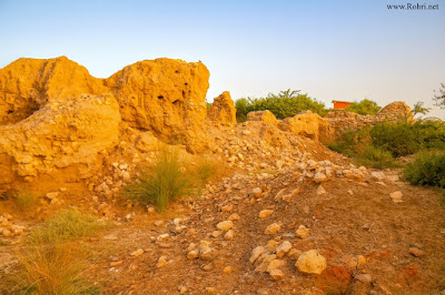 Aror Ruins at Golden Hour β Ancient Sindh Historical Site Near Rohri Golden sunset light on rocky hills and ancient stone structure at Aror (Alor) ruins near Rohri Sindh Pakistan with green vegetation