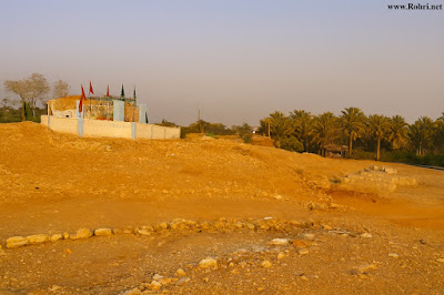 Hasil Shah’s Hilltop Shrine – Umarkas Wah, Rohri Shrine of Hasil Shah atop the hill near Umarkas Wah, Rohri — sacred site surrounded by rocky terrain, flags, and palm trees. A cultural landmark reflecting Sindh’s spiritual heritage and historical landscape.