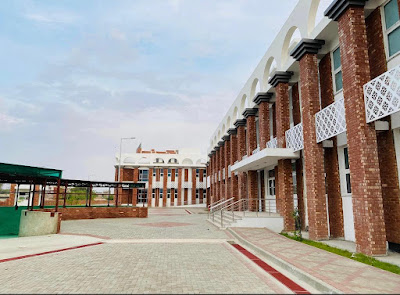 Contemporary Institutional Architecture – Red Brick Columns and Accessible Campus Design Institutional building with tall red brick columns, white balcony railings, arched roof elements, and accessible walkways in a landscaped campus setting.