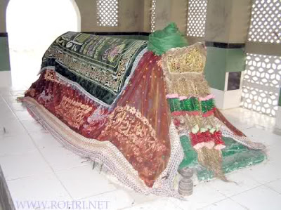 Shah Maqsood Shrine Rohri – Sindh’s Embroidered Legacy of Sufi Devotion Indoor shrine of Shah Maqsood in Rohri, Sindh – covered with green, red, and gold embroidered cloths