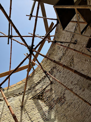 Shaikh Laloo Pir Shrine – Interior Dome Construction with Bamboo Scaffolding in Rohri, Sindh Interior view of Shaikh Laloo Pir Shrine in Rohri, Sindh, showing circular brick walls under construction with bamboo scaffolding arranged across the open dome, metal framework near the top, and unfinished masonry work.