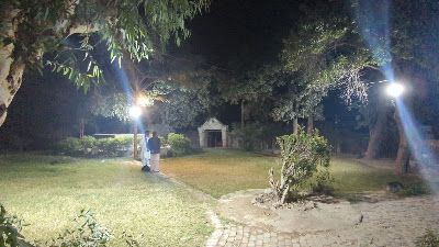 Evening Gathering at Tekchand Bolchand Park Sukkur Pavilion Visitors standing near the historic domed pavilion at night in Tekchand Bolchand Park Sukkur, with pathway and lights, Sindh historical park Pakistan